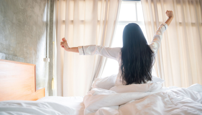 Girl facing to the window stretching early in the morning