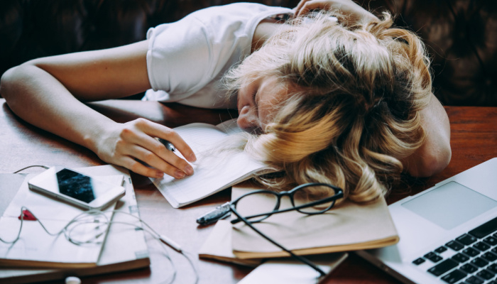 A teenage girl sleeping on her table while doing her school homework procrastinating